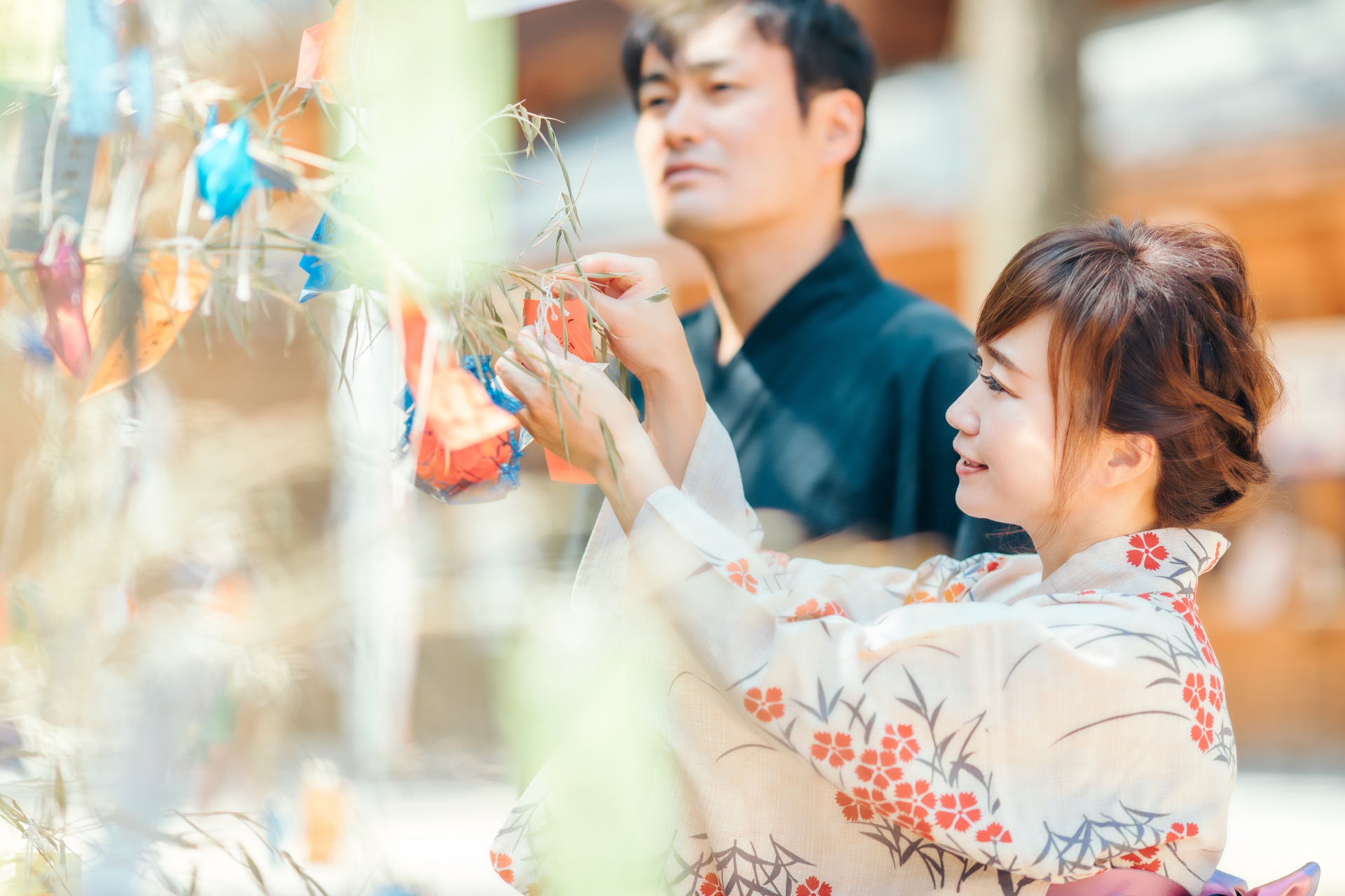 A man and a woman hanging wishes on paper strips